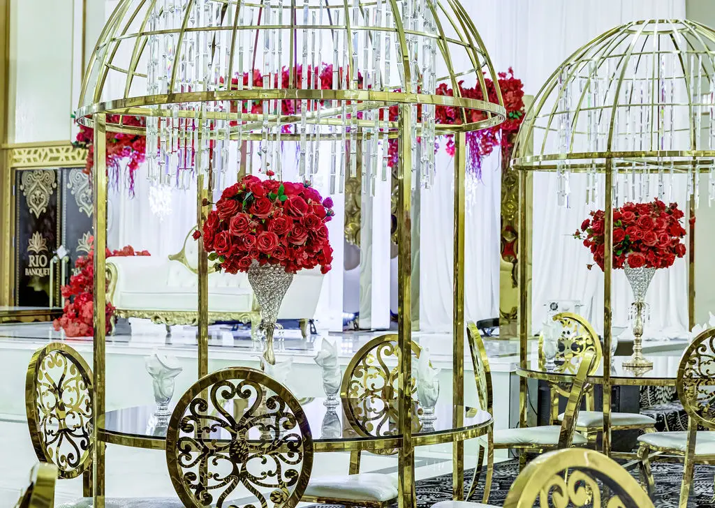 Gold birdcage décor with red rose arrangements beside a dining table