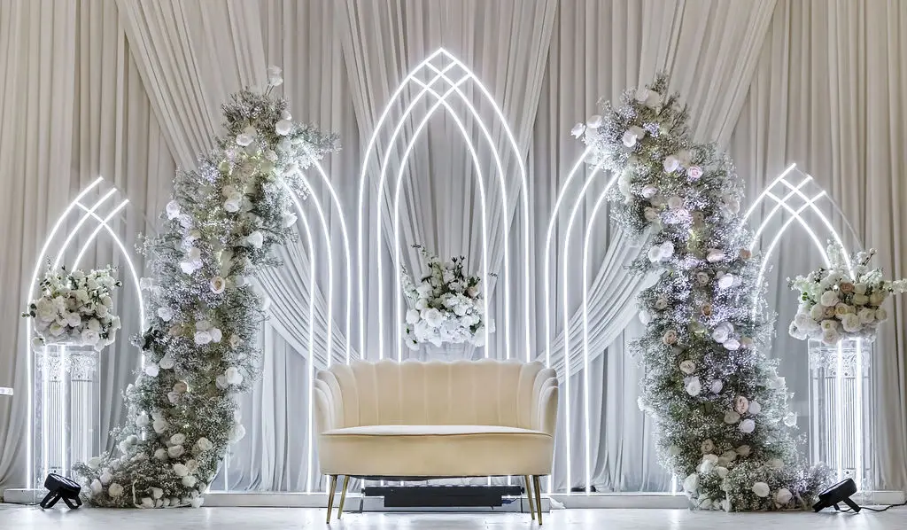 Wide view of a white arched wedding stage with floral columns