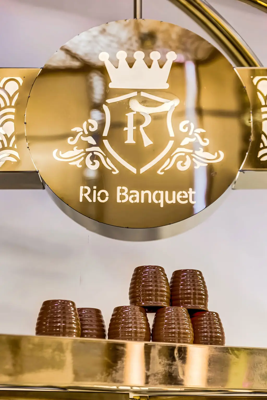 Gold RIO Banquet crest sign above a stack of clay kulhad cups