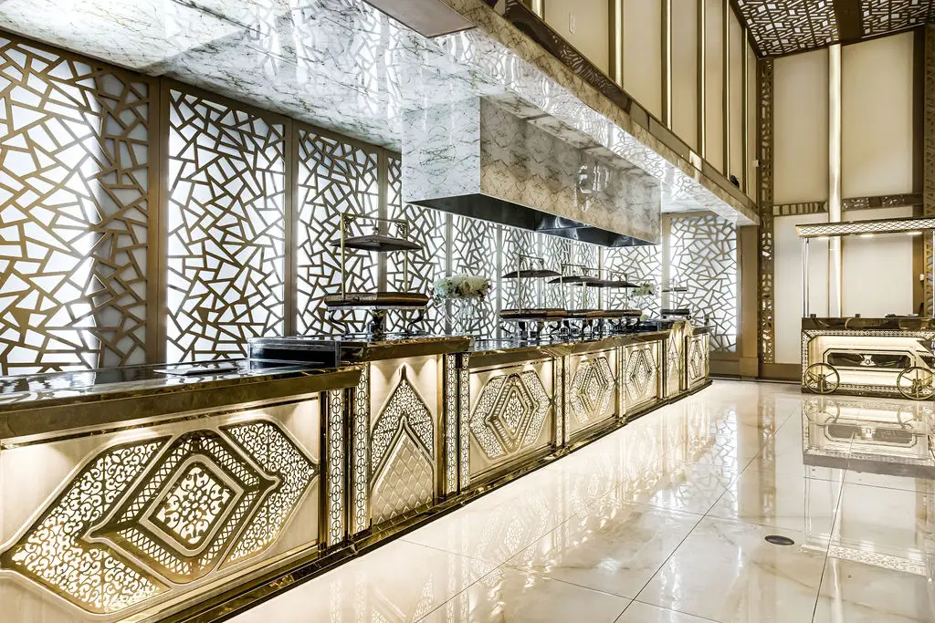 Live cooking stations framed by backlit gold lattice screens and marble floors