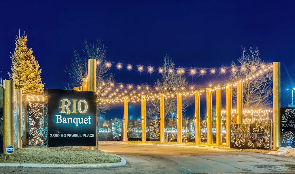 RIO Banquet roadside sign at 2850 Hopewell Place glowing at night beside a lit tree and colonnade