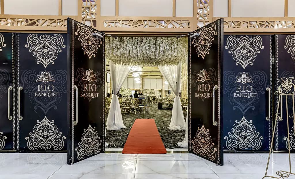 Open black and gold crest doors revealing a red-carpet aisle and floral canopy
