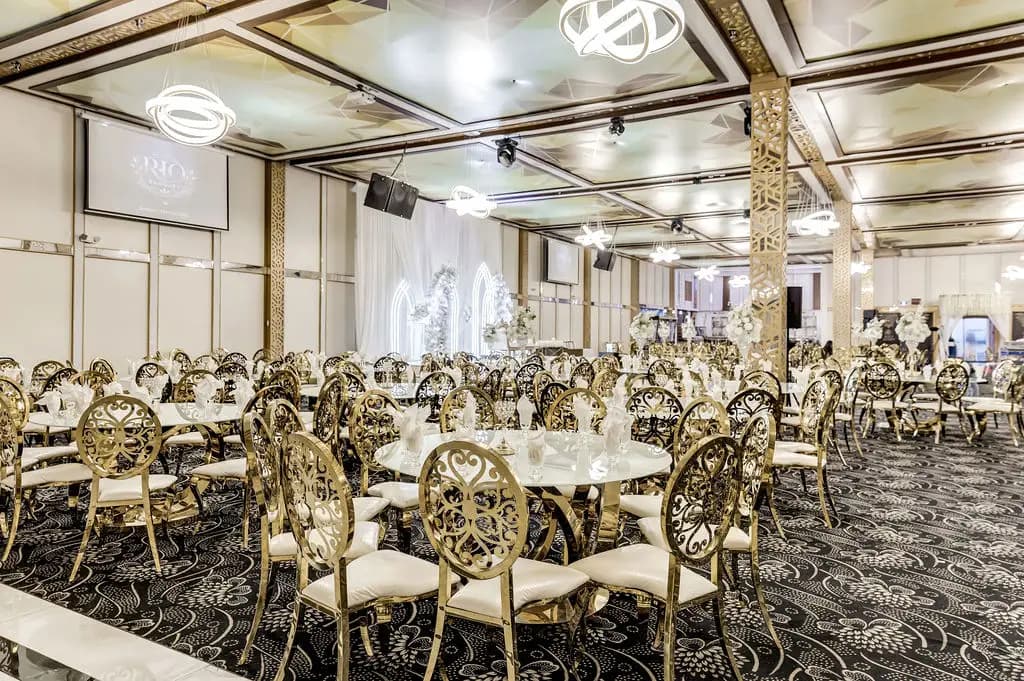 Banquet hall laid with gold filigree chairs around marble tables